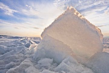 Gelb-orangefarbenes Licht der Sonne scheint durch eine Eisscholle, einen Erdhügel auf dem Baikalsee  von Michael Semenov