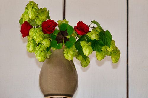 Petit bonheur dans un vase avec des roses, du houblon et le trèfle à quatre feuilles
