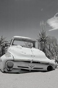 Oud verroest en verlaten oldtimer autowrak in het zand. Zen, rust. Zwart wit