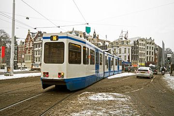 Tram rijd door een besneeuwd Amsterdam in Nederland van Eye on You