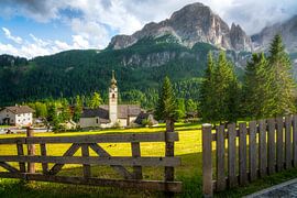 Die Kirche von Colfosco mit Holzzaun und den Dolomiten im Hintergrund, Italien von Stefano Orazzini