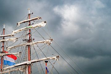 Oude mast en zeilen met donkere wolken