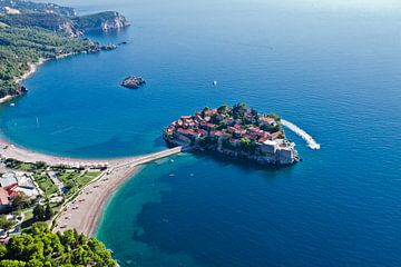 Vlucht over het eiland stad (Sveti Stefan). landschap onder (luchtfoto van een paraglider) met de ku