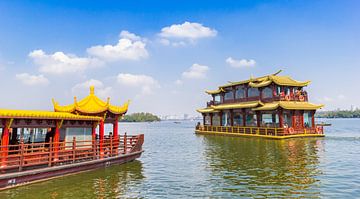 Rondvaartboten in traditioneel chinese bouwstijl op het West Lake meer van Hangzhou van Marc Venema