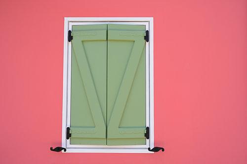 Eine Wand in leuchtendem Korallenrot mit geschlossenen grünen Fensterläden