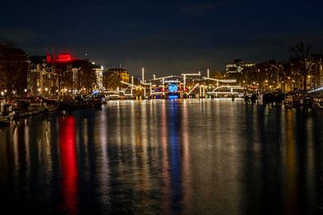 Amsterdam bei Nacht mit der beleuchteten Skinny Bridge an der Amstel in den Niederlanden von Eye on You