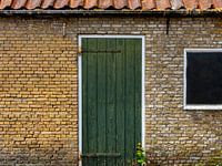 Groene deur in gebouw van oude, gele bakstenen.