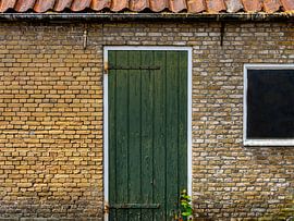 Groene deur in gebouw van oude, gele bakstenen. von René van der A
