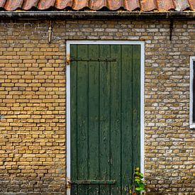 Green door in building from old, yellow bricks. von René van der A