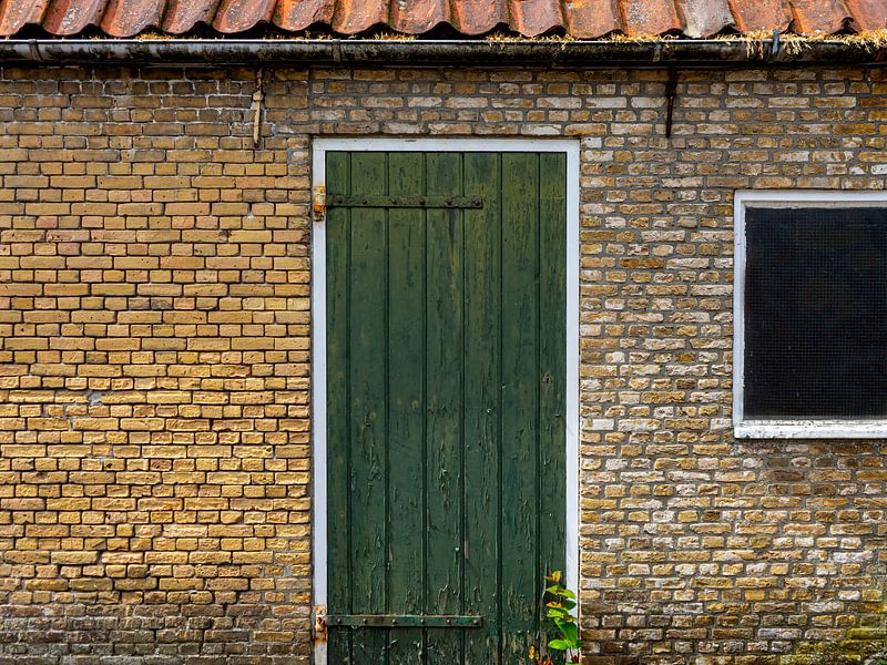 Green door in building from old, yellow bricks. by René van der A
