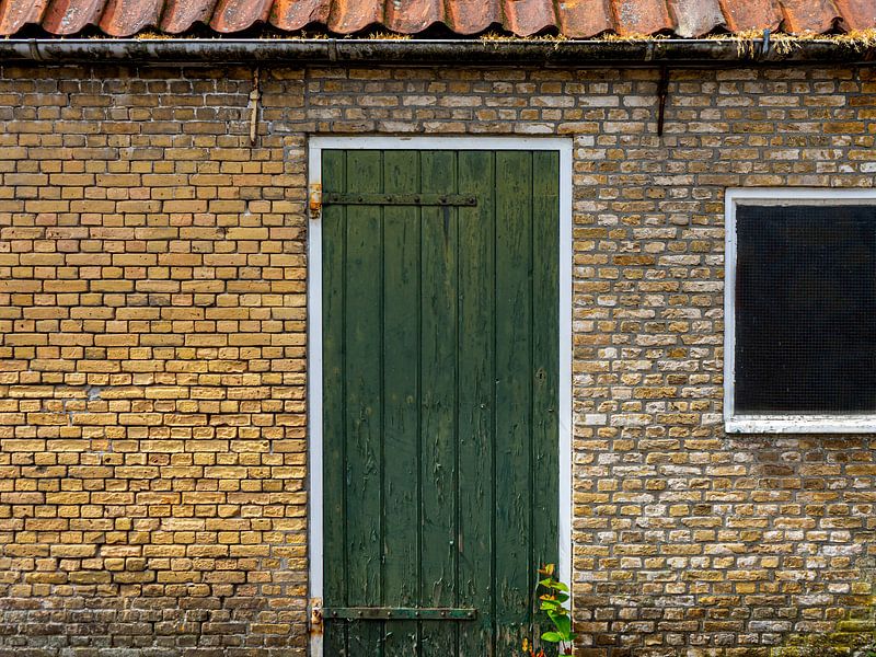 Groene deur in gebouw van oude, gele bakstenen. van René van der A