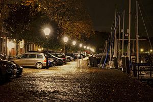 Geparkeerde auto's in nachtelijk Veere, mooi verlicht op een glimmende straat van Gert van Santen