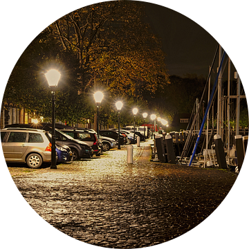 Geparkeerde auto's in nachtelijk Veere, mooi verlicht op een glimmende straat van Gert van Santen