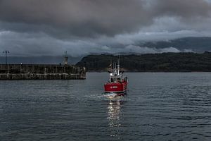Ein kleines Fischerboot verlässt den Hafen kurz vor Einbruch der Dunkelheit.