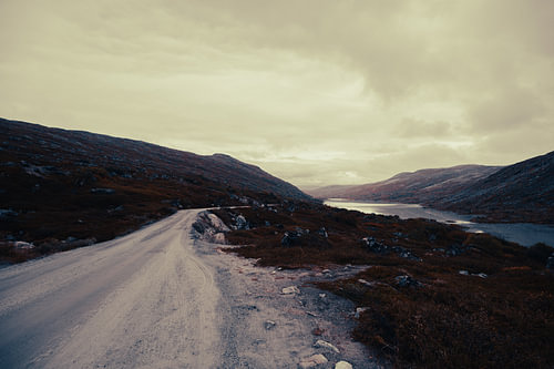 A gravel path by the dark mountain lake