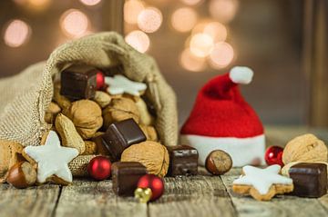 De zak en de kap van Kerstmis santa met noten, koekjes en fonkelende lichtenachtergrond van Alex Winter