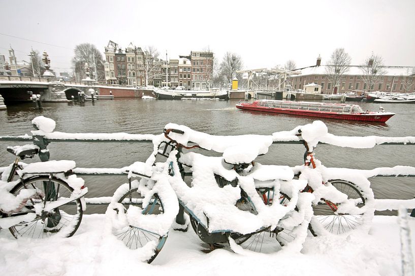 Besneeuwde fietsen aan de rivier de Amstel in Amsterdam van Eye on You