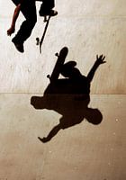 Een skateboarder springt over zijn schaduw