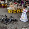 Meisje in klederdracht voert duiven op de markt in Malta van Eric van Nieuwland