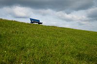 Stilleven foto van een blauw bankje op een dijk