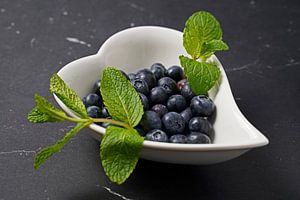 Blaubeeren mit Pfefferminzblättern in einer Schale