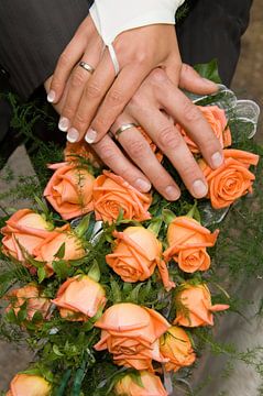 Hands of a wedding couple on the bridal bouquet by Jörg B. Schubert