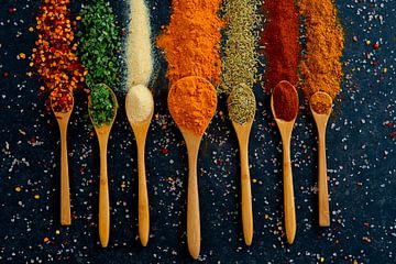 Colourful spices and herbs on wooden spoons by Francis Dost