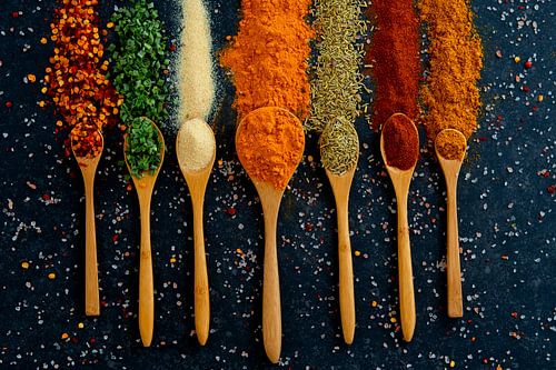 Colourful spices and herbs on wooden spoons