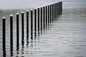 Schwarze Verankerungspfähle oder Dalben aus Beton im Wasser, Ende