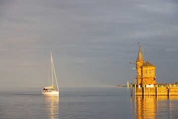 Konstanz aan het Bodenmeer, haveningang met vuurtoren, schepen, weerspiegelingen bij oranje zonsondergang van Andreas Freund