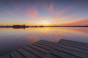 Lever de soleil coloré depuis la jetée de l'Oude Veer à Anna Paulowna, avec vue sur le moulin à vent et un beau reflet sur l'eau calme.