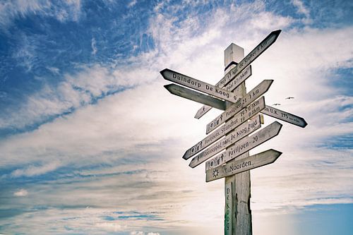 Signpost against blue cloud sky