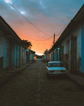 Orangefarbener Sonnenaufgang in einer Straße in Trinidad de Cuba mit einem Oldtimer