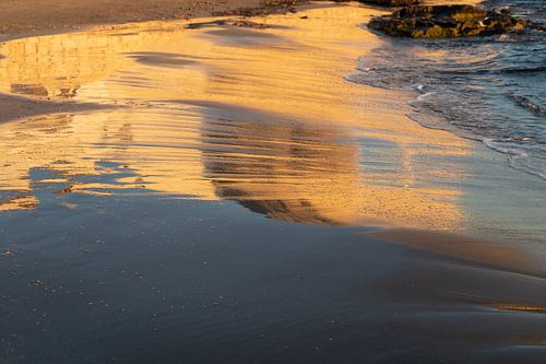 Avondlicht weerspiegeld in het natte zand