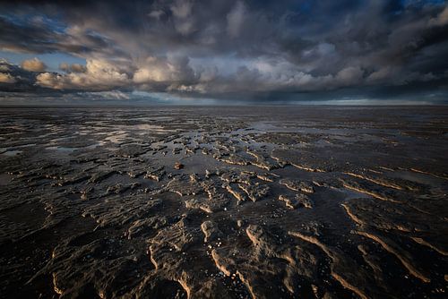 Dreigende wolkenluchten boven de waddenzee. Bij laag water blijv