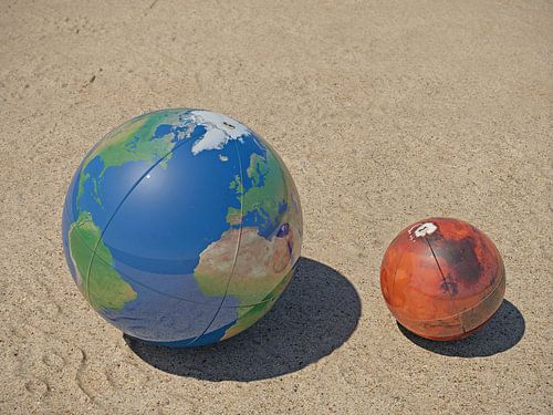 De Aarde en Mars op het strand