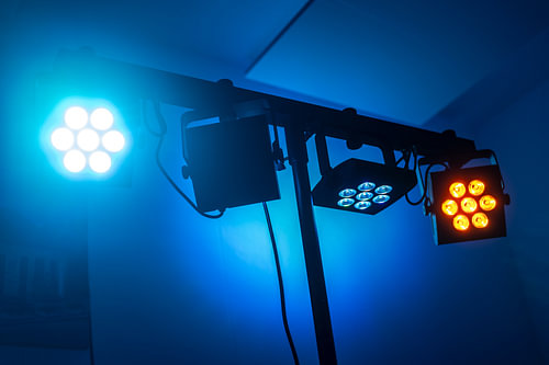 Farblich abgestimmte LED-Scheinwerfer an einer Traverse vor einem dunkelblauen Gebäude
