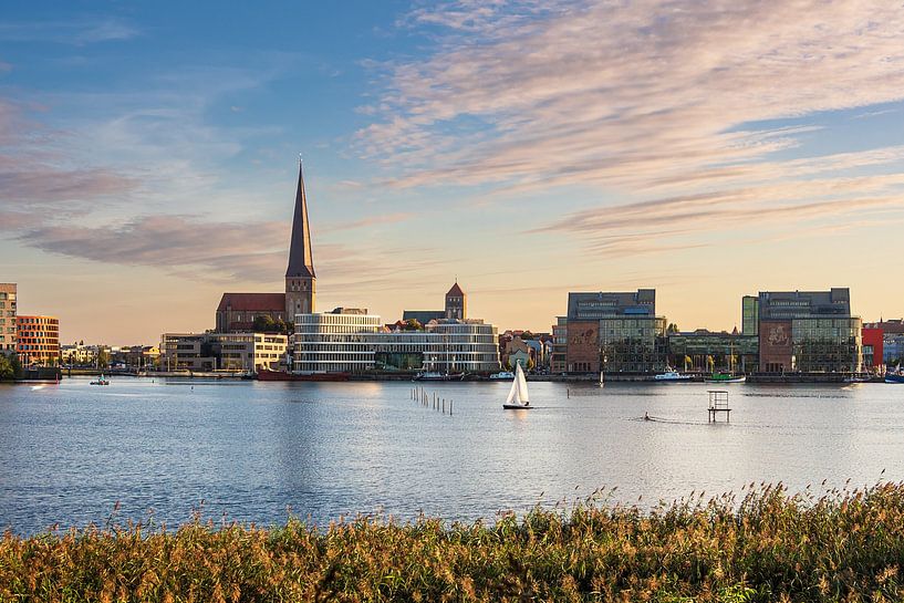 Uitzicht over de Warnow naar de Hanzestad Rostock in de avond van Rico Ködder