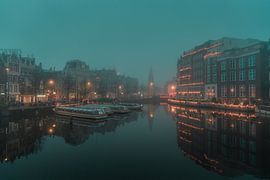 Amsterdam Canal in the Mist – Bridge with Warm Reflections by Thea.Photo