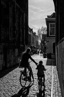 Moeder en kind fietsen onder de Dom