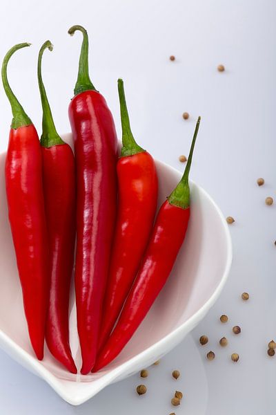 Hot en Spicy, Rode peper in witte stenen schaaltje en losse peper op de witte achtergrond by John Westerveld