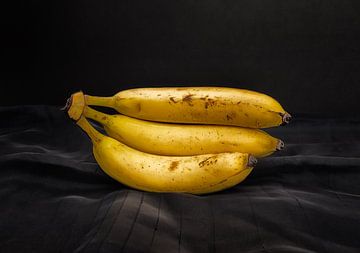 Een tros van drie bananen op een mooi belichte donkere ondergrond. van René Ouderling