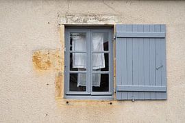 Blauer Rahmen und Fensterladen in einer alten französischen Fassade mit zum Trocknen aufgehängter Wäsche von Birgitte Bergman
