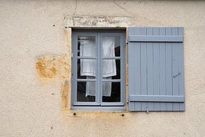 Blauer Rahmen und Fensterladen in einer alten französischen Fassade mit zum Trocknen aufgehängter Wäsche