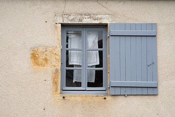 Blauw kozijn en luik in oude Franse gevel met was die hangt te drogen