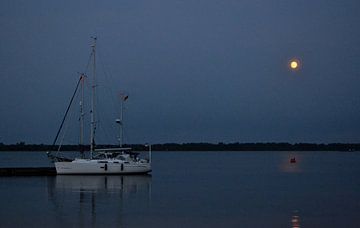 Zeilboot bij avondlicht. Heldere maan die weerspiegelt in het water. van Marianne Hoekman