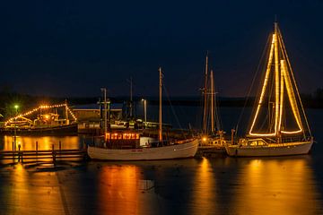 Dekorierte Segelboote zu Weihnachten im Hafen von Lauwersoog in den Niederlanden bei Sonnenuntergang von Eye on You
