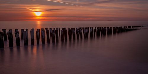 Zonsondergang met golfbrekers