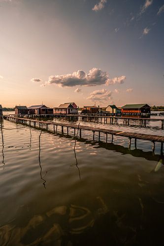 Loopbrug in het meer naar de zonsondergang met huizen