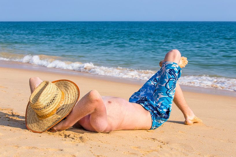 Toerist met hoed zonnebaadt op strand van Ben Schonewille
